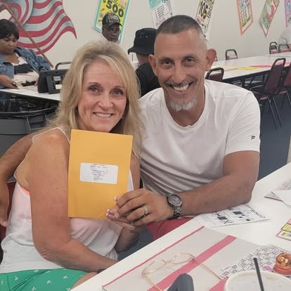 Two people holding a yellow envelope together
