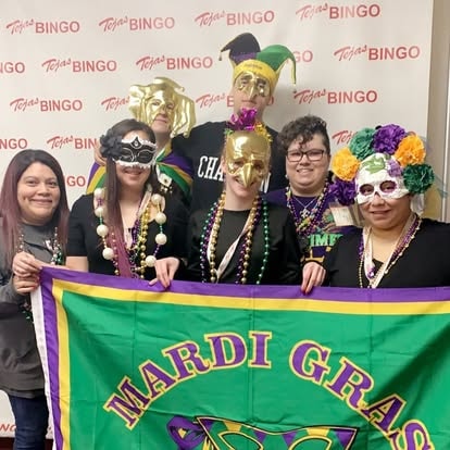 Group celebrating Mardi Gras with beads and banner