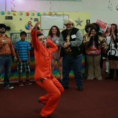 Children and adults dancing at a classroom celebration